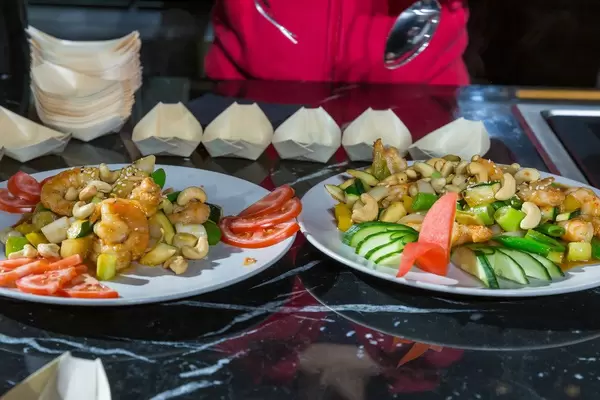 Shrimps, nuts, spring onions and colourful vegetables served on white plates