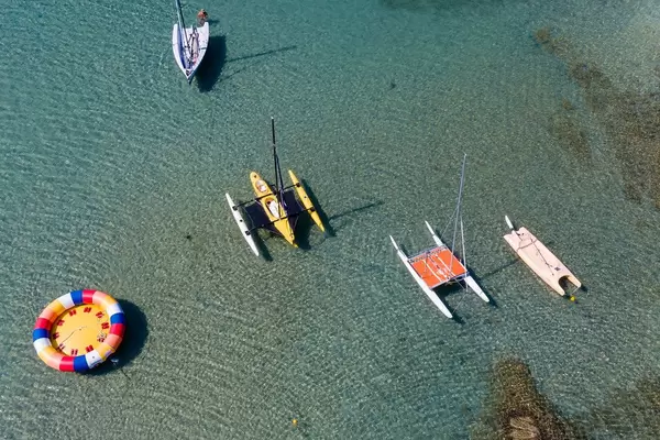 Sicht von oben auf eine bunte Schlauchbootinsel und kleine Katamarane auf dem klaren Wasser des Mittelmeers vor Paros, Griechenland