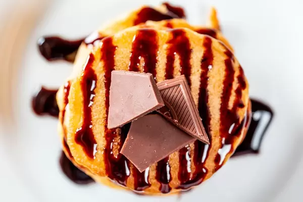 Sicht von oben auf einen Pfannkuchenstapel, mit Schokostückchen und Schokoladensauce