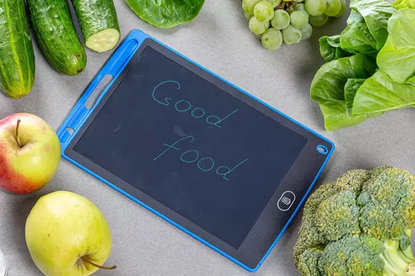 Sicht von oben auf frisches, reifes Obst und Gemüse, neben der Aufschrift - Gute Lebensmittel - auf grauem Hintergrund"