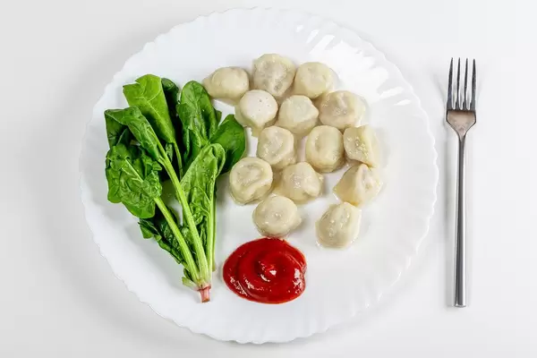 Sicht von oben auf Knödel mit Spinat und Tomatensauce