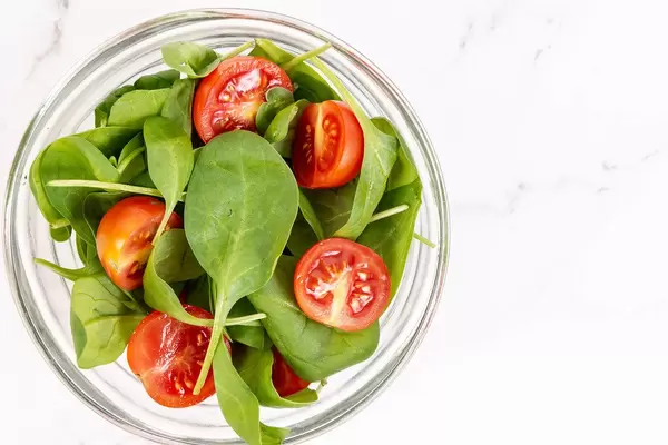 Sicht von oben: Schüssel mit Cherry Tomaten und Babyspinat auf weißem Hintergrund