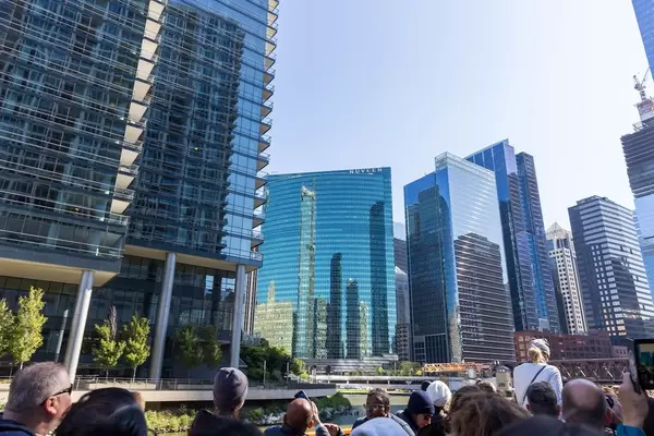 Sightseeing boat tour in Chicago: tourists admiring the reflections of other skyscrapers on the curves of the 333 Wacker Drive highrise building