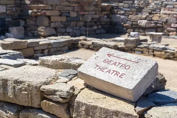 Sign on a stone pointing the way to the ancient theatre of Delos, written in English and Greek