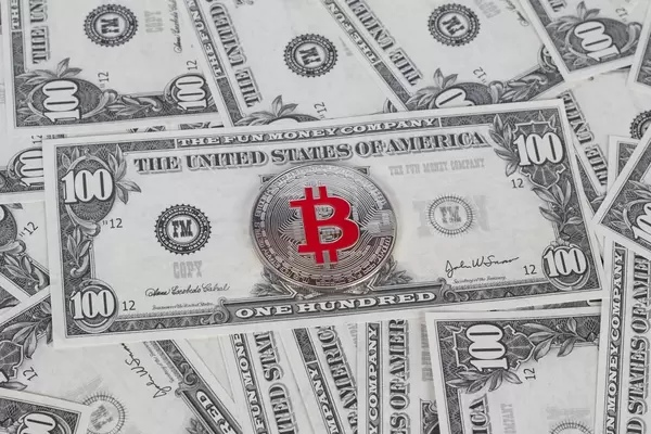 Silberne Münze der Bitcoin Kryptowährung auf 100 USD Banknote