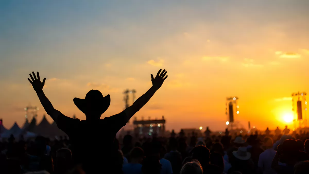 Silhouette mit Cowboyhut beim Musikfestival im Sonnenuntergang