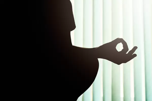 Silhouette of a young woman doing yoga - Gyana Mudra
