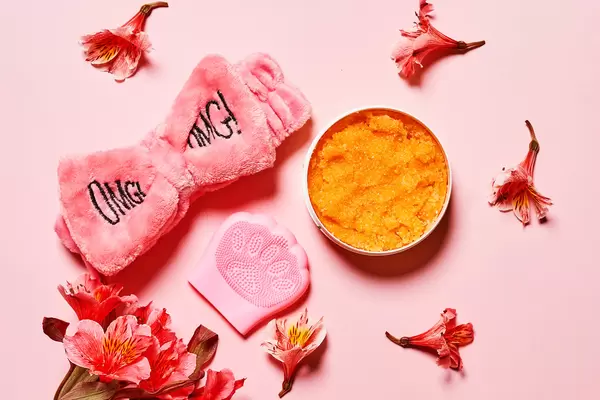 Silicon hand massager and relaxing cream on pink background