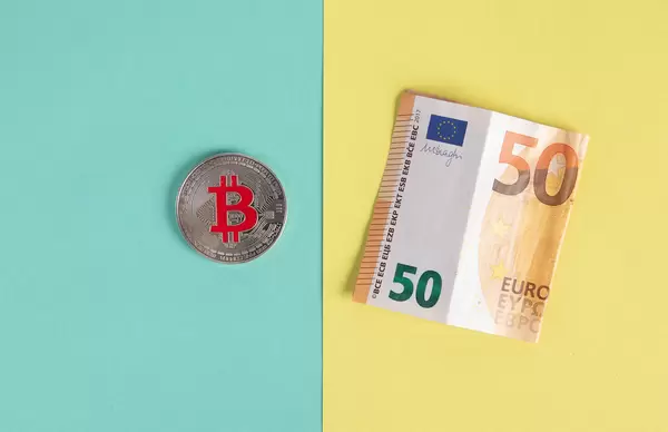 SIlver Bitcoin coin and folded 50 Euro banknote