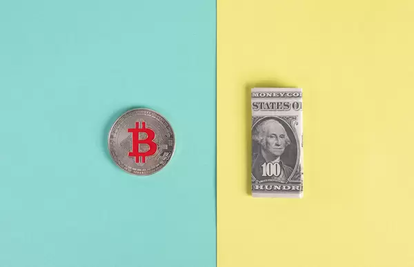 SIlver Bitcoin coin and folded one hundred dollar banknote