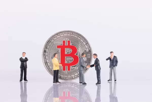 Silver Bitcoin coin with group of businessman