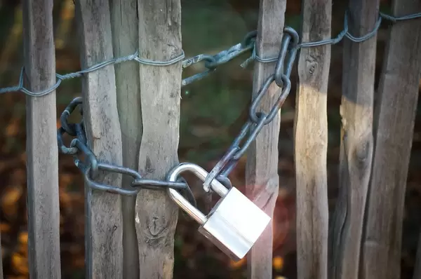 Silver Padlock and Chain closing a Wooden Gate