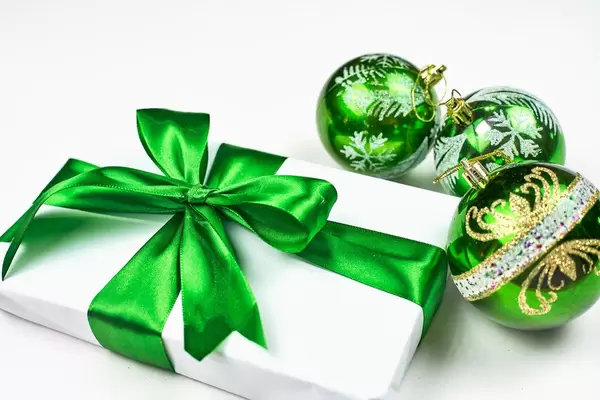 Simple classic wrapped gift box with green ribbon bow and festive holiday decorations