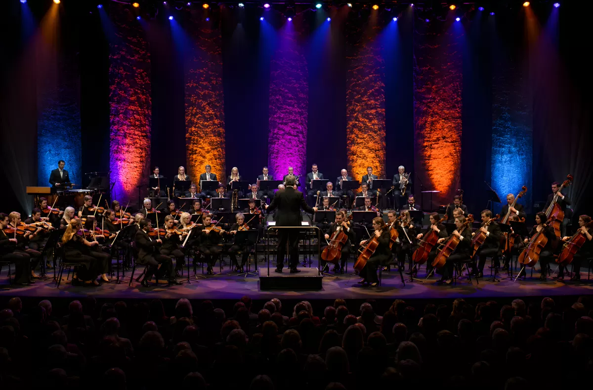 Sinfonieorchester auf beleuchteter Bühne mit Dirigent