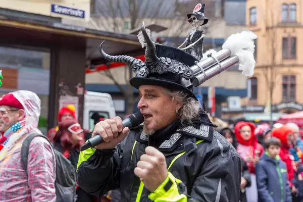 Singer at German carnivals procession with creative carnivals costume hat and skeleton addresses exhaust pollution