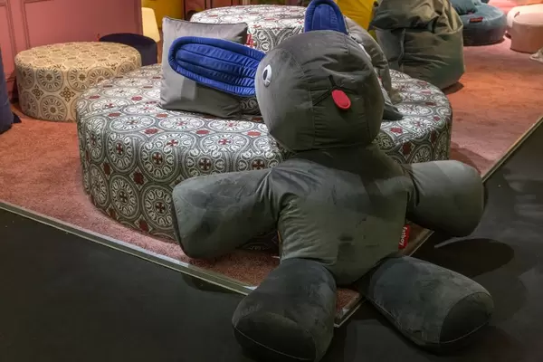 Sitzpuff in Form eines riesigen Hasen lehnt sich an rundes Sofa mit auffälliger Musterung an