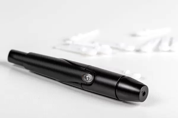 Skin lancing device with replaceable needles