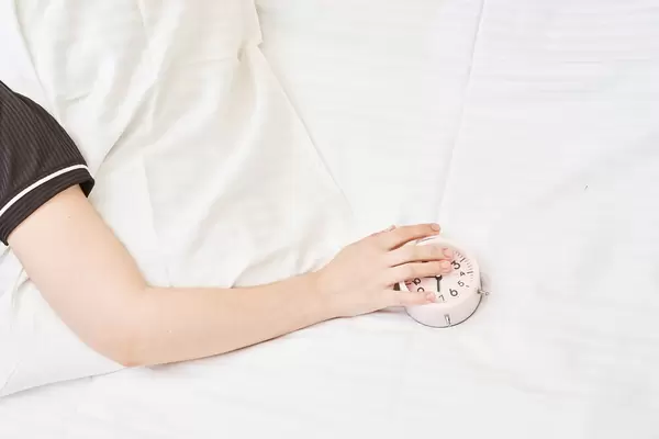 Sleeping woman and alarm clock in bedroom at home