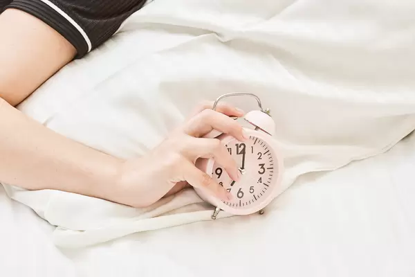 Sleepy female trying kill alarm clock