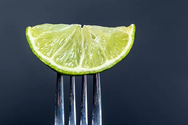 Slice of lime on a fork on a black background