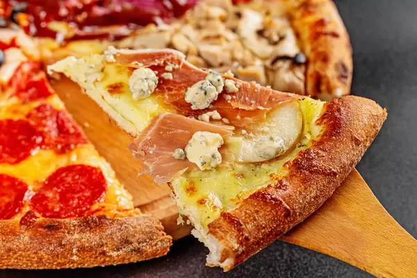 Slice of pizza with mozzarella, pear and dor blue cheese, close-up