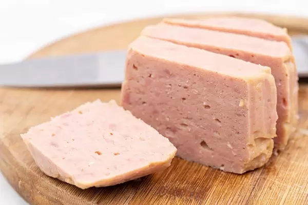 Sliced and served Luncheon Meat on the wooden cutting board