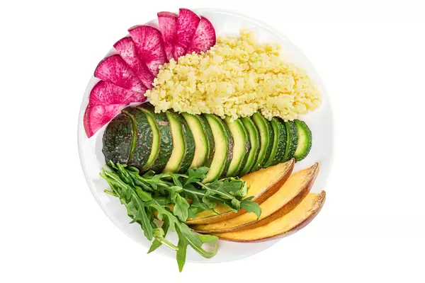 Sliced avocado, mango, red radish, arugula leaves and couscous, healthy food concept