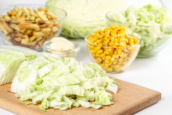 Sliced chinese cabbage with corn and croutons, salad preparation