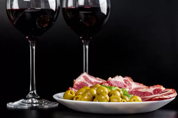 Sliced dried meat with olives and glasses of red wine