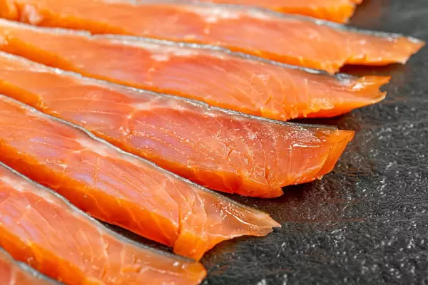 Sliced fillet of smoked red fish on a black background