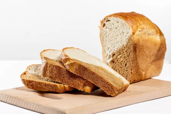 Sliced fresh bread on a cutting board in white background