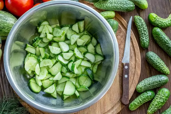 Sliced fresh cucumbers in an iron bowl, top view