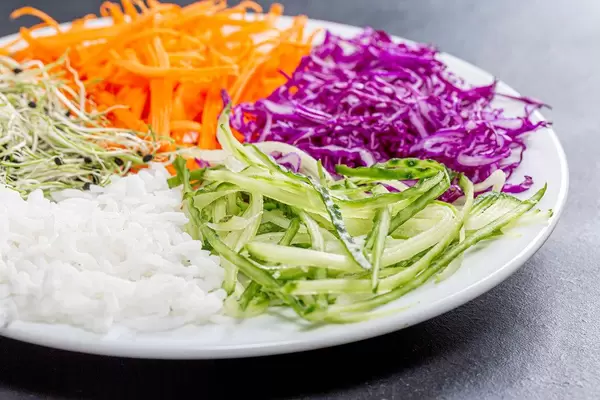 Sliced fresh vegetables and rice on a plate closeup