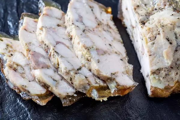 Sliced homemade ham on black stone background