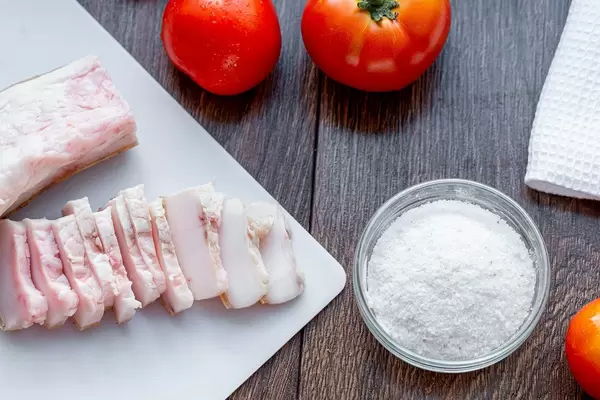 Sliced lard with salt and fresh tomatoes on the table (Flip 2019)