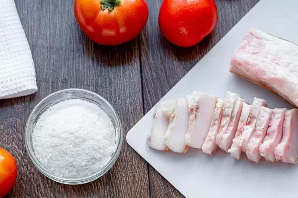Sliced lard with salt and fresh tomatoes on the table