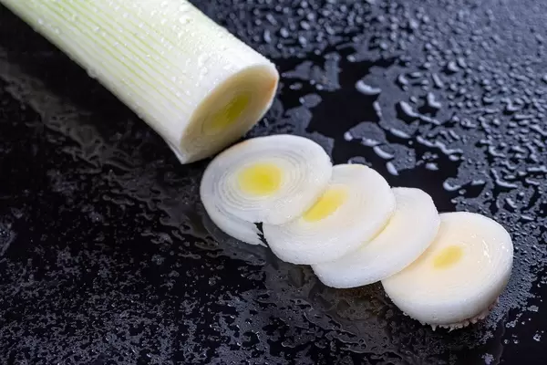 Sliced leek rings on black background with water drops (Flip 2019)