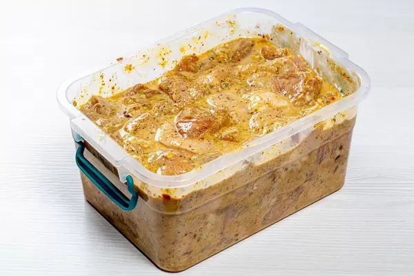 Sliced meat marinated with spices in a plastic container for barbecue