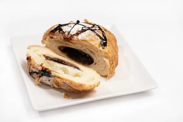 Sliced pastry croisant with chocolate and powdered sugar on the plate