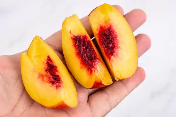 Sliced Peach in the hand above white background