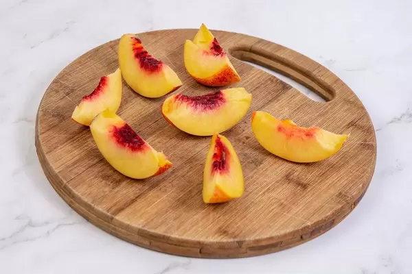 Sliced Peach on the round wooden board