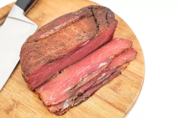 Sliced piece of Smoked Ham on the round wooden board (Flip 2020)