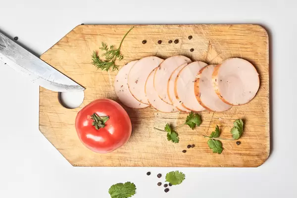 Sliced pieces of smoked chicken meat on wooden cutting board