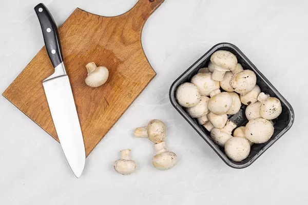 Sliced Raw Mushrooms on the table with cutting board