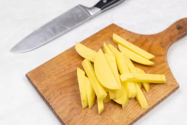 Sliced raw potatoes on the wooden cutting board