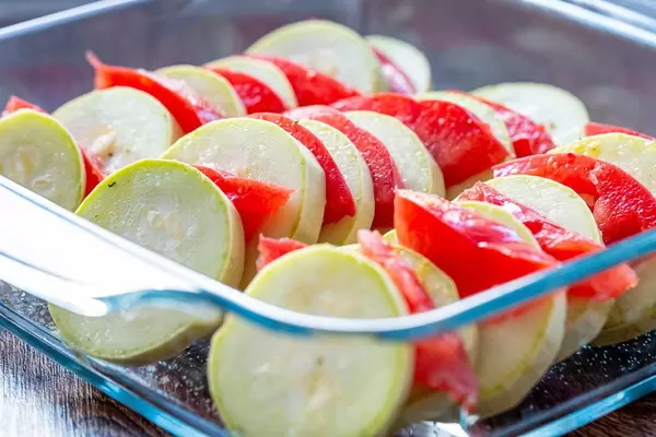 Sliced raw zucchini and tomatoes in a glass pan
