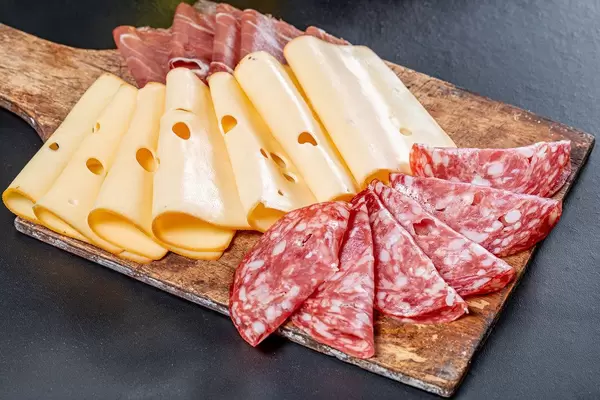 Sliced salami, ham, jerky and cheese on an old wooden kitchen Board (Flip 2019)