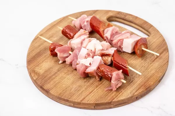 Sliced sausage bacon and meat on the wooden grill stick (Flip 2019)