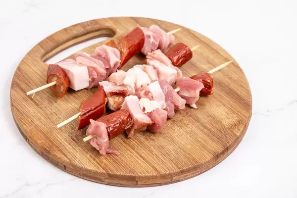 Sliced sausage bacon and meat on the wooden grill stick