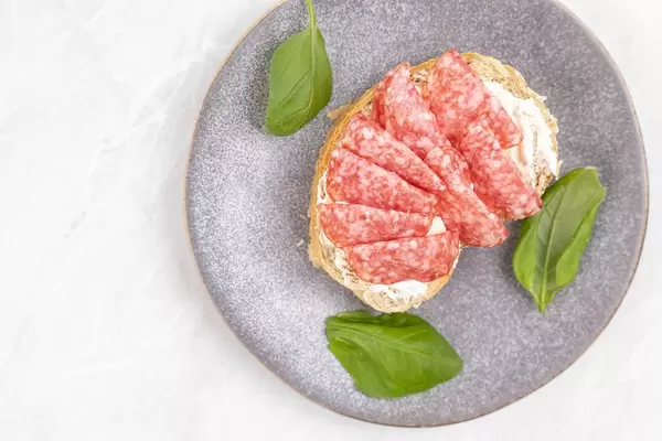 Sliced Sausage served on the bread with Basil leaves